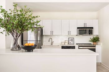 A kitchen with white cabinets and a white countertop.